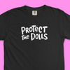 Closeup of black Comfort Colors trans rights shirt with hand written text that says "Protect the Dolls" in white.